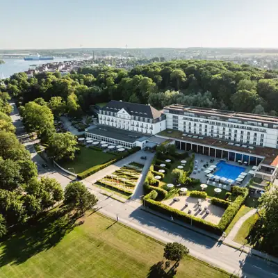 A-ROSA Travemünde Großes Gebäude mit Pool, umgeben von Bäumen.