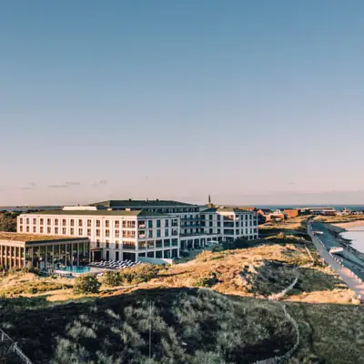 A-ROSA Sylt Ein großes Gebäude neben einem Gewässer.