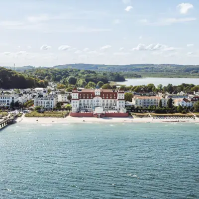Kurhaus Binz Ein großes weißes Gebäude neben einem Gewässer.
